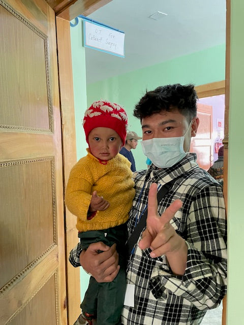 A volunteer holding a young child at a Skinjuvea medical outreach clinic